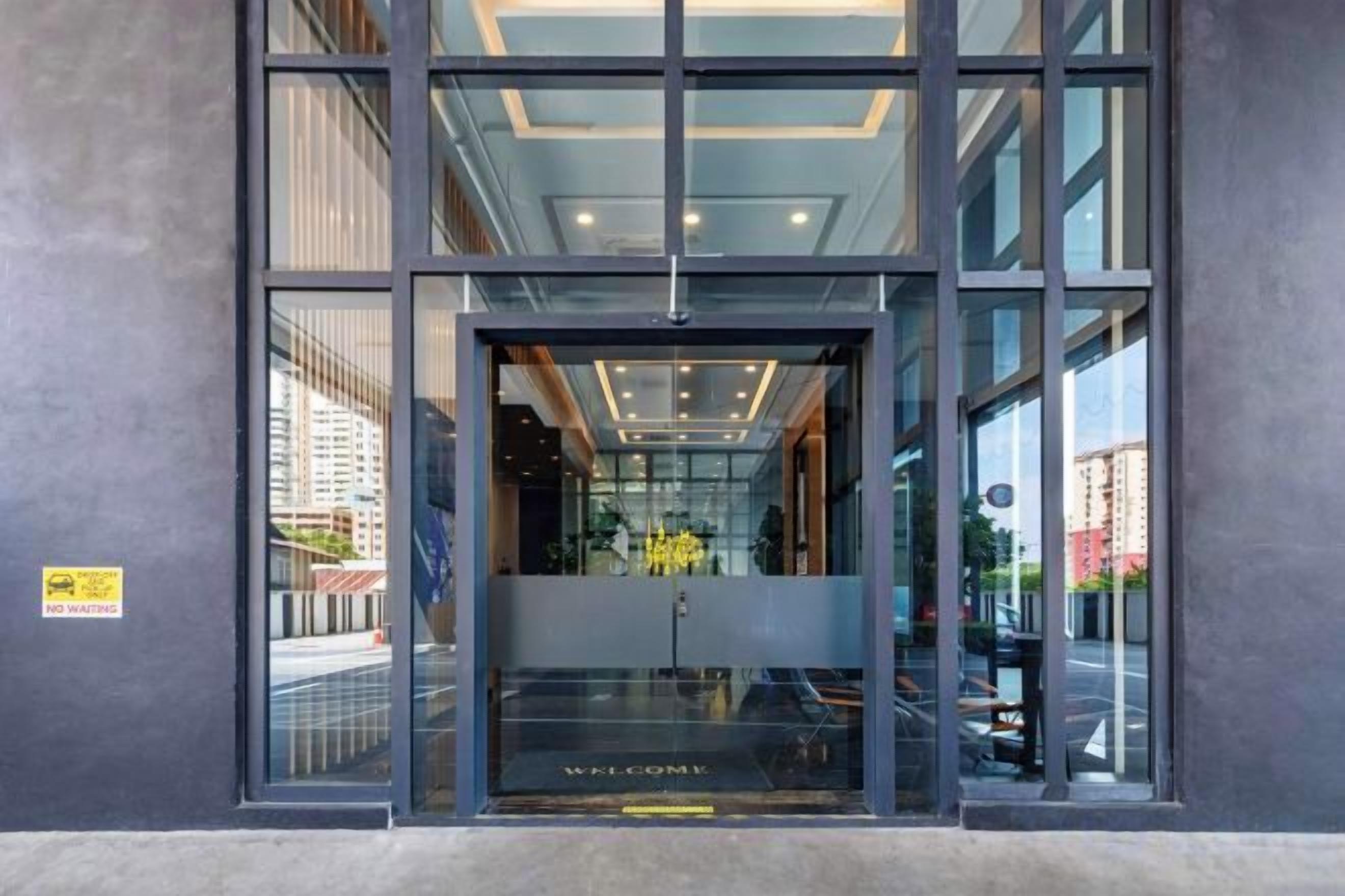 A modern building entrance with a glass door and a 'WELCOME' sign.