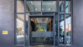 A modern building entrance with a glass door and a 'WELCOME' sign.