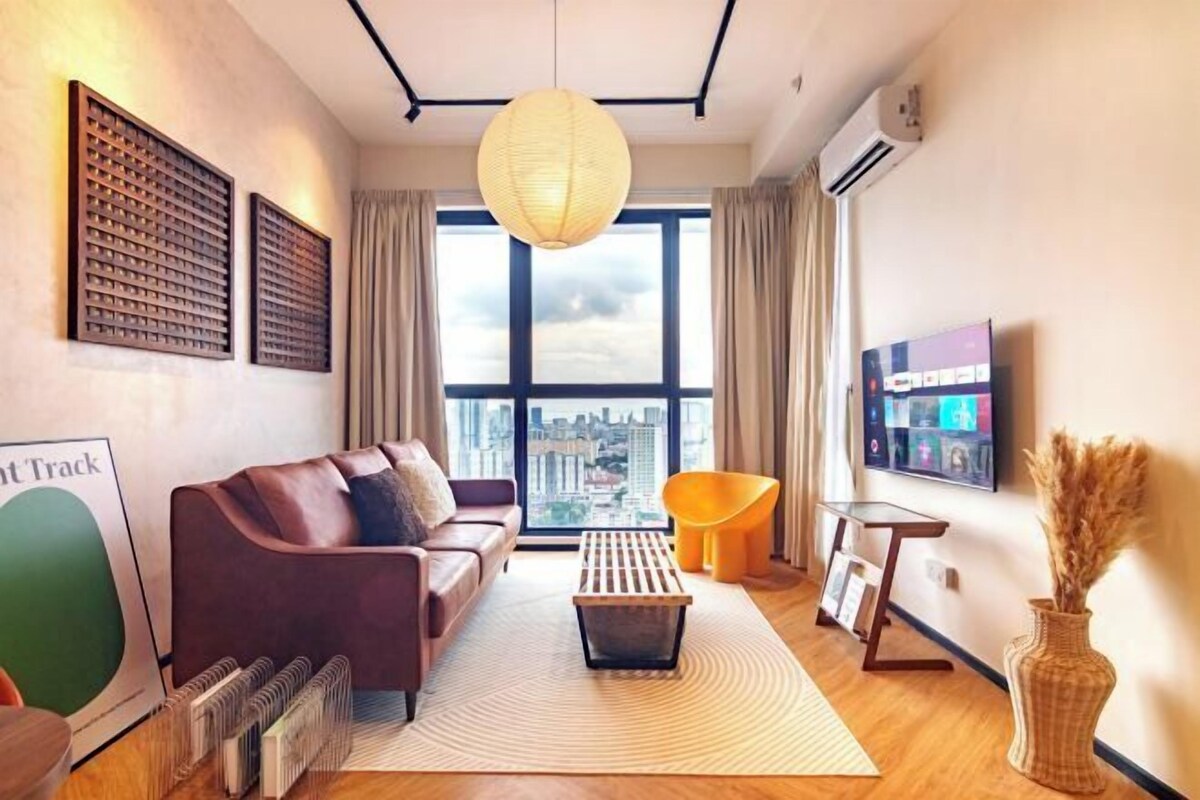 A modern living room with a sofa, a coffee table, a TV, and a large window with a city view.