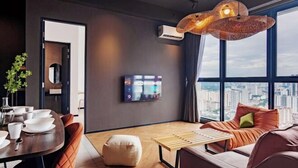 Un soggiorno moderno con zona pranzo, un'ampia finestra vista città e un originale lampadario intrecciato.