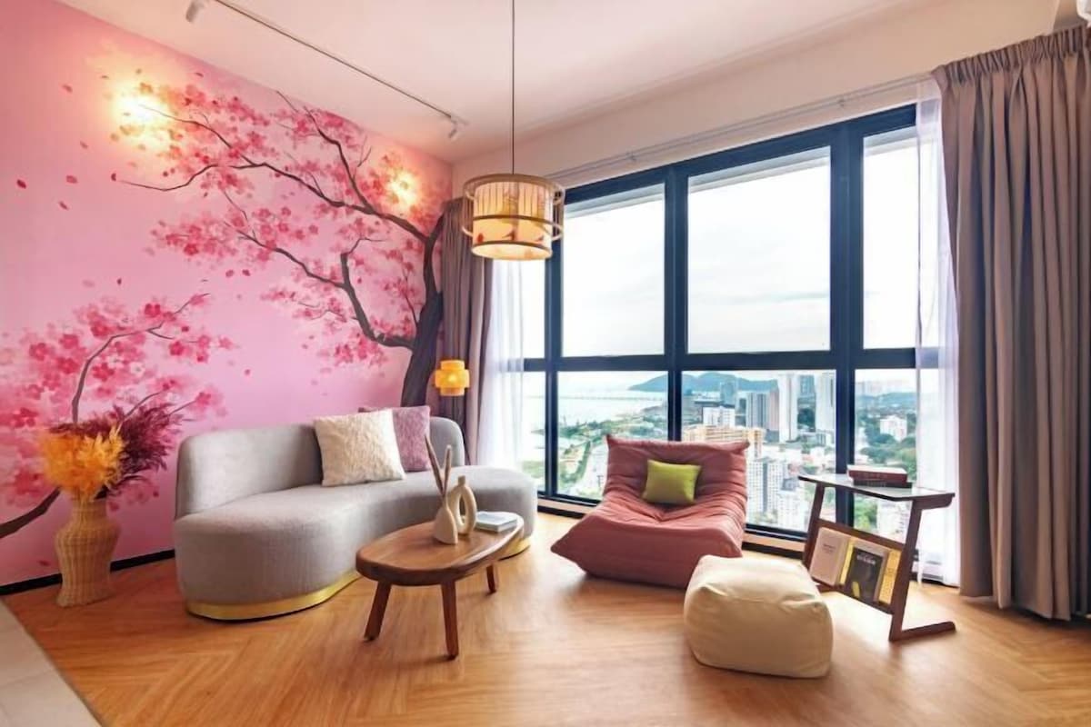A modern living room with a large window, a sofa, a chair, a coffee table, and a decorative wall mural.