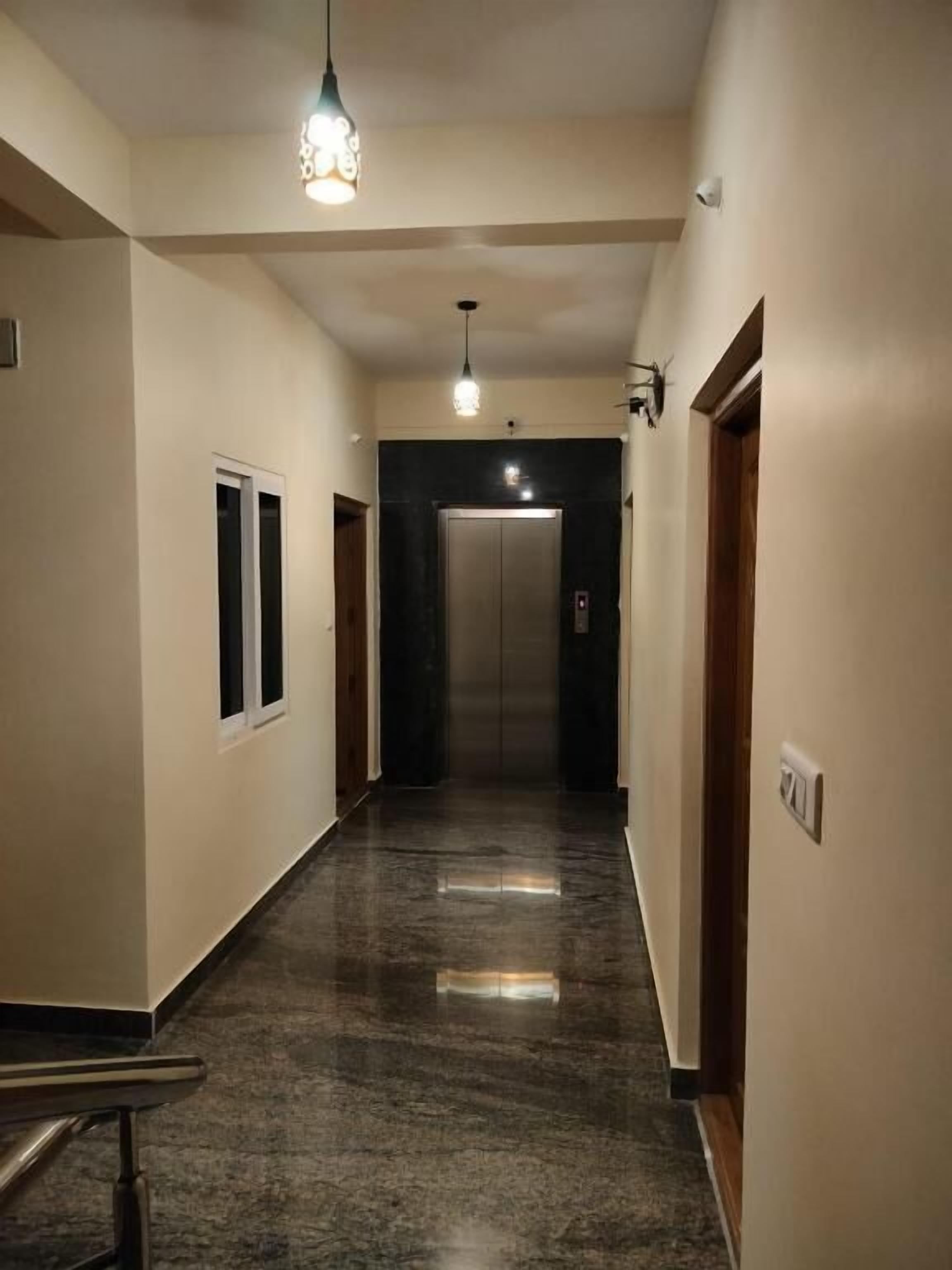 A hallway with a marble floor, a light fixture, and an elevator.