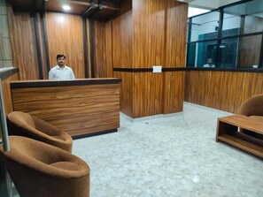 A reception area with a wooden reception desk, plush seating, and a marble floor. - Golden Chariot (Bengaluru)