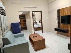 A compact living space with a sofa, a coffee table, a TV unit, and a mirror. - Golden Chariot (Bengaluru)