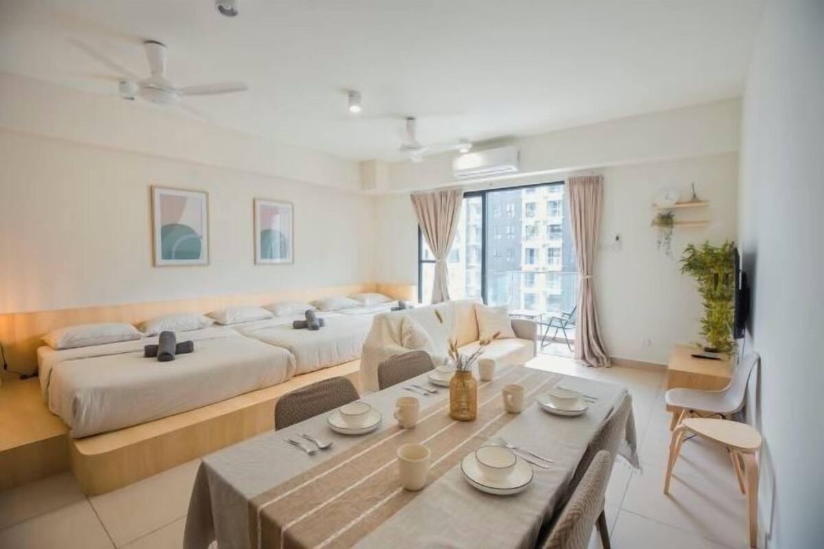Una habitación de hotel moderna con una cama, una mesa de comedor para dos personas y un ventanal con vistas a edificios.