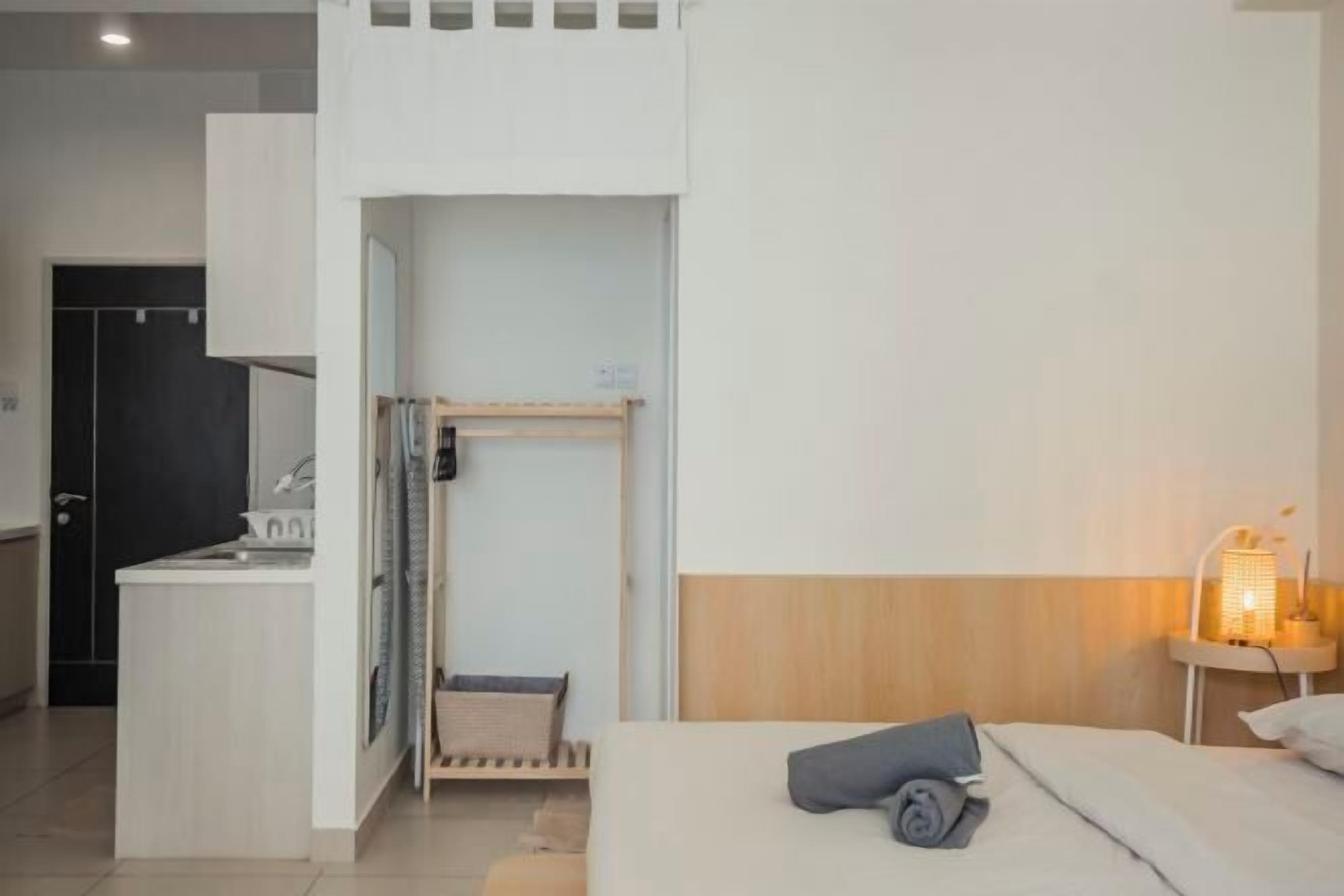A hotel room with a bed, bedside lamp, and a small desk area.