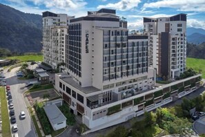 A multi-story hotel with a modern design, featuring a prominent 'SCAPES' sign on the facade, surrounded by lush greenery and a mountainous backdrop. - Studio Zen@Midhills Genting Highlands (Free WiFi) (Genting Highlands)