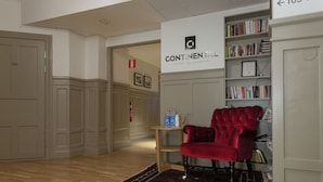 A hallway with a red chair, a bookshelf, and a sign that reads "CONTINENTAL extended stay apartments."