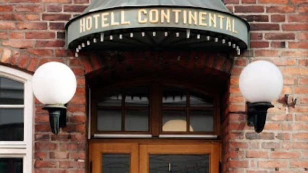 A brick building with a wooden double door and a sign above reading "HOTEL CONTINENTAL".