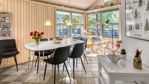 A modern dining area with a round table, black chairs, and a vase of red roses.