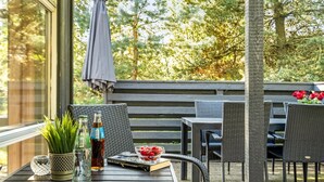 A patio with outdoor furniture, a table with drinks and a book, and a view of trees.
