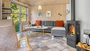 A cozy living room with a fireplace, wooden walls, a sofa, and a dining table.