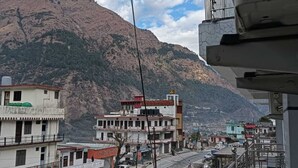 A street view with buildings, a mountain in the background, and a clear sky. - Hotel Nirvanam (Chamoli)