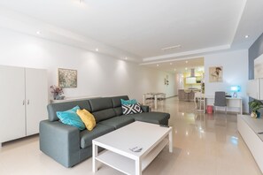 A modern living room with a grey sofa, a white coffee table, and a dining area in the background. - St.Julians apartment (San Gwann)