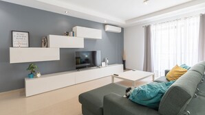 Un soggiorno moderno con un divano grigio, un tavolino da caffè bianco e una TV a schermo piatto.