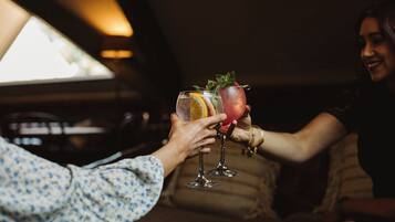Two people toasting with drinks in a dimly lit room.
