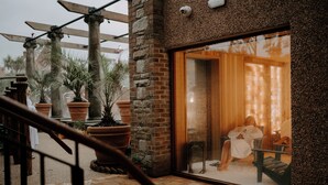 Un espace de détente avec un mur en pierre, une porte en bois et une personne qui se relaxe à l’intérieur.