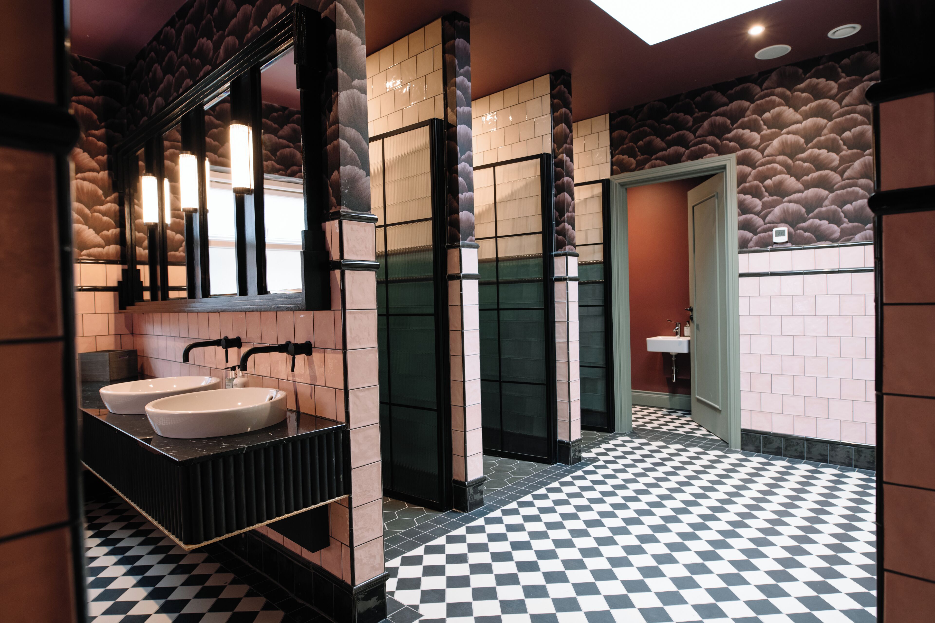 Une salle de bain moderne avec deux lavabos, un grand miroir et un carrelage à motifs géométriques.