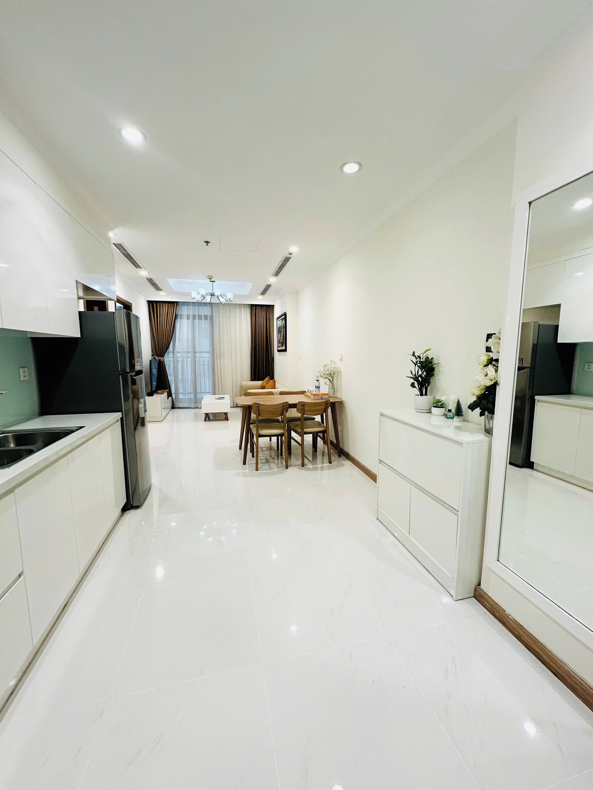 A modern kitchen with white cabinetry, a built-in stove, and a dining area with a table and chairs.