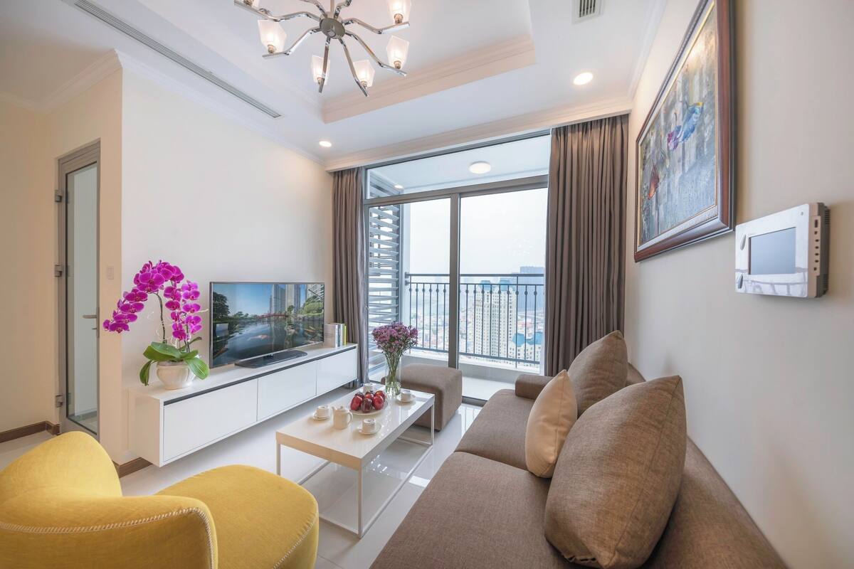 A modern living room with a flat-screen TV, a sofa, a yellow armchair, and a coffee table.