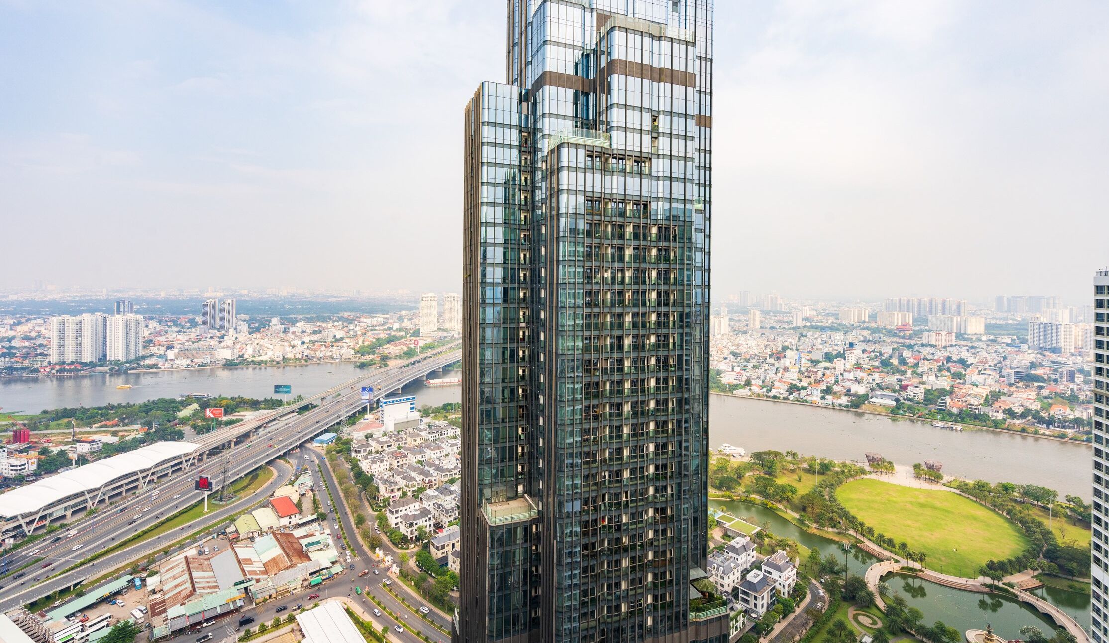 A high-rise building with a modern glass facade, surrounded by a river and a mix of residential and commercial buildings.