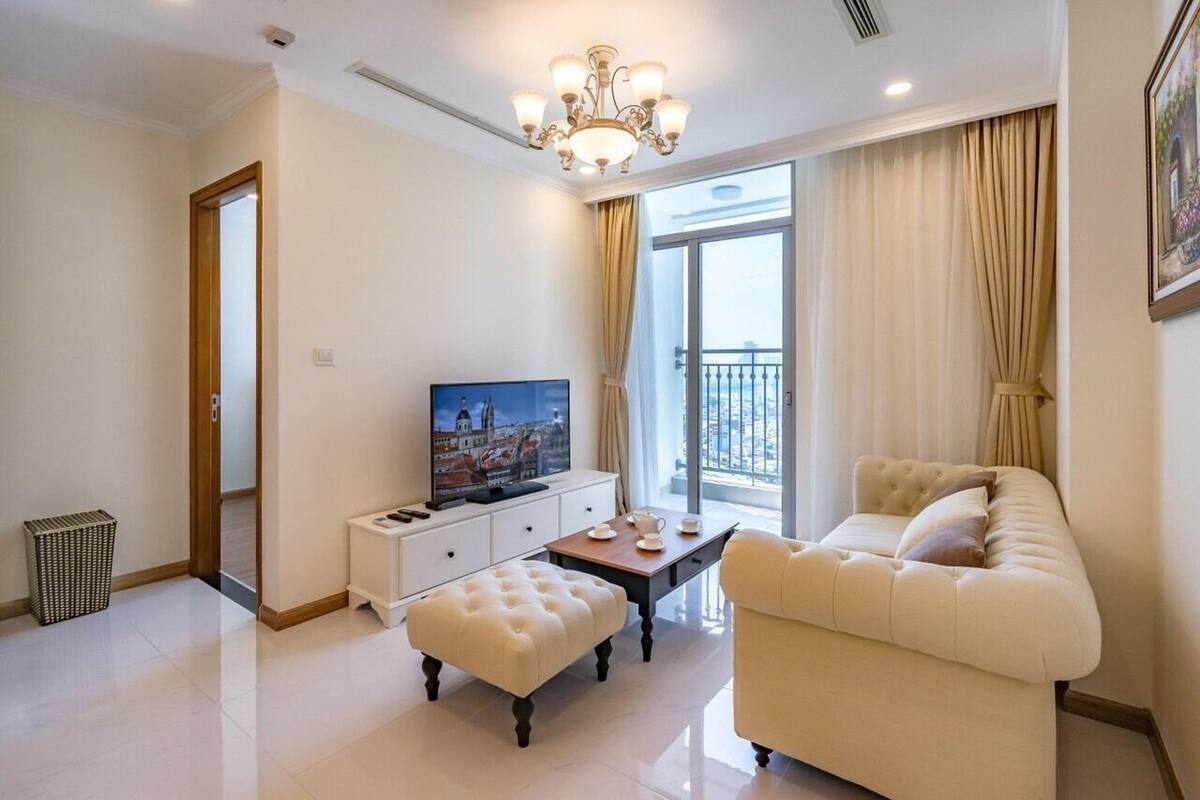 A modern living room with a television, a sofa, a coffee table, and a window with curtains.