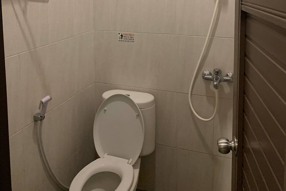 A small, modern bathroom with a toilet, a shower, and a hand dryer.