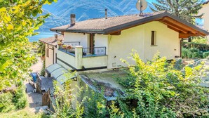 A two-story house with a balcony, a satellite dish, and a mountain view. - Beautiful  villa for 4 people with WIFI, TV, terrace and pets allowed (Porlezza)