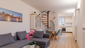 A modern living room with a grey sofa, a glass coffee table, and a cityscape painting. - Beautiful apartment for 6 guests with TV and patio (Arco)