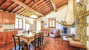 A rustic kitchen with wooden beams, a stone wall, and a fireplace. - Stunning  villa for 12 guests with WIFI, private pool, TV, balcony, pets allowed and panoramic v... (Greve In Chianti)