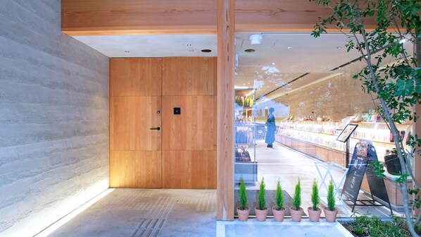 Un interior moderno con una puerta de madera, un camino con pavimento táctil y plantas en macetas.