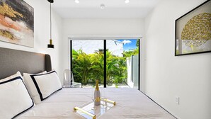 A modern bedroom with a bed, a clear glass tray, and a bottle of champagne. - Calm Miami Oasis -Secluded Patio (Miami)