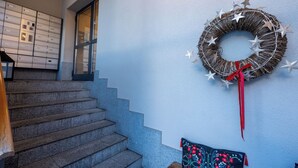 Un escalier menant à une pièce dont un mur est bleu, ornée d’une guirlande décorative et d’un coussin à motifs.