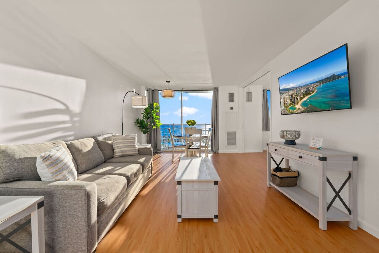 A modern living room with a sofa, coffee table, and a TV displaying a scenic view.