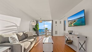 A modern living room with a sofa, coffee table, and a TV displaying a scenic view.