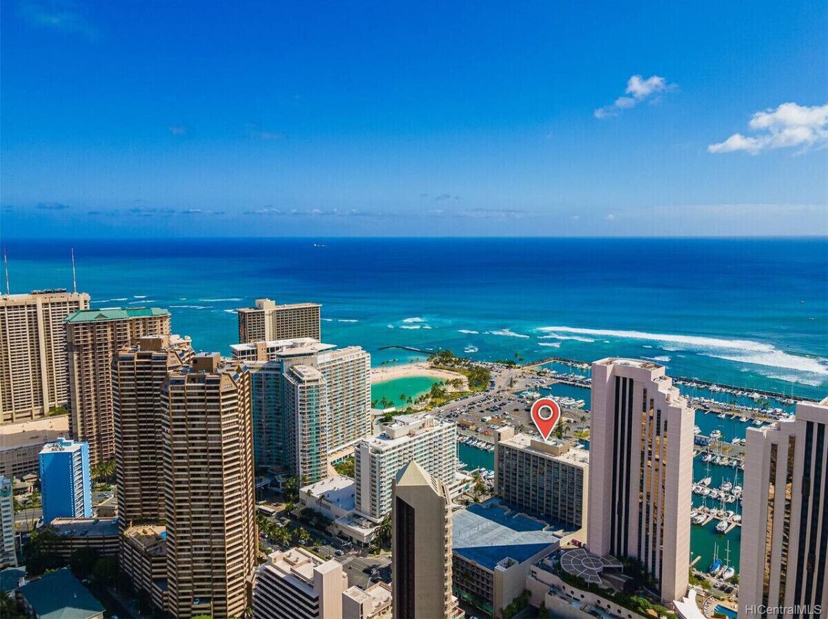 A coastal cityscape with high-rise buildings, a marina, and a clear view of the ocean.