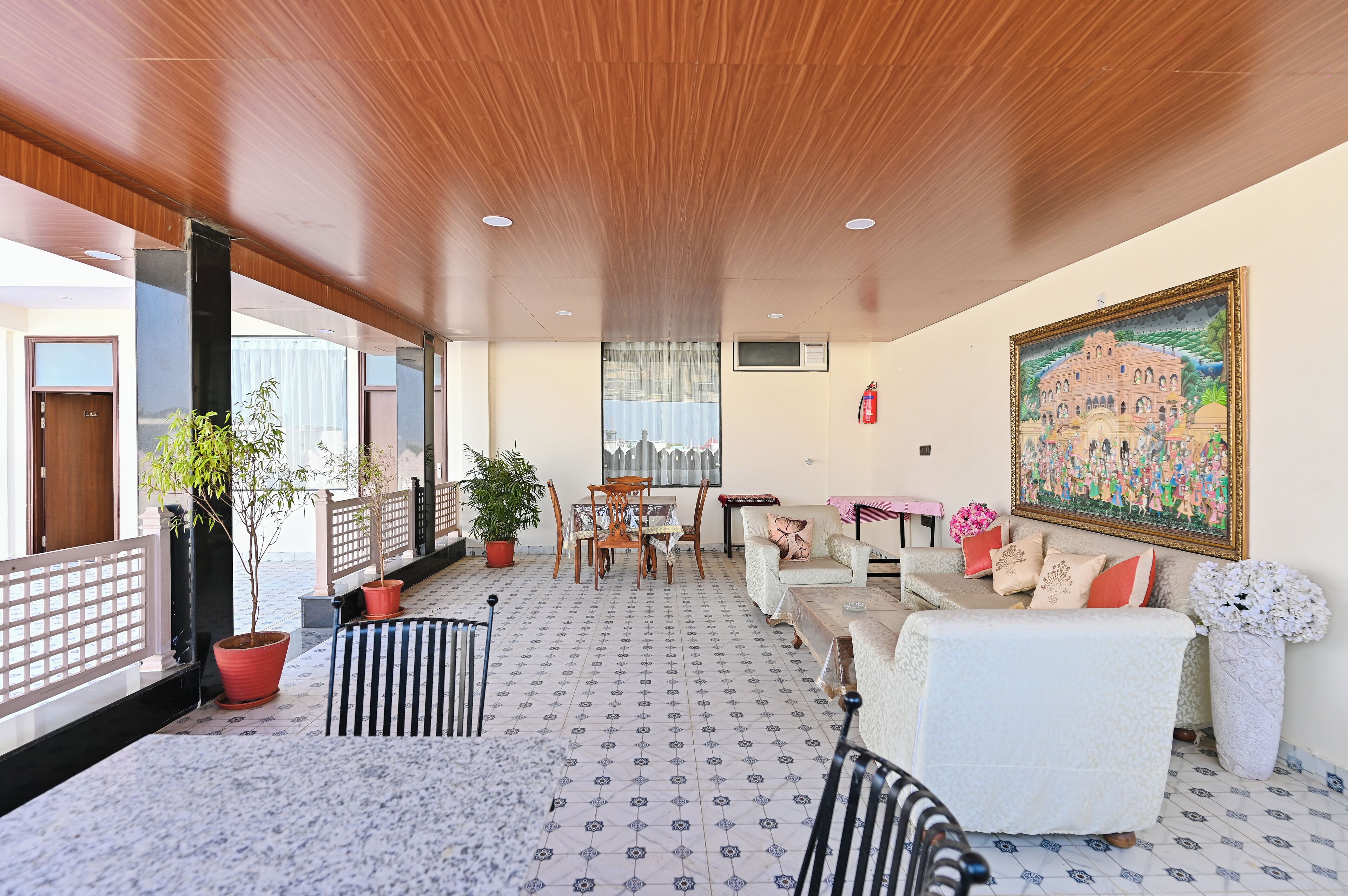 Ein geräumiges Zimmer mit Holzboden, einem gemusterten Bodenbelag, einer Essecke mit Tisch und Stühlen, einer Sofagarnitur und einem großen Gemälde an der Wand.