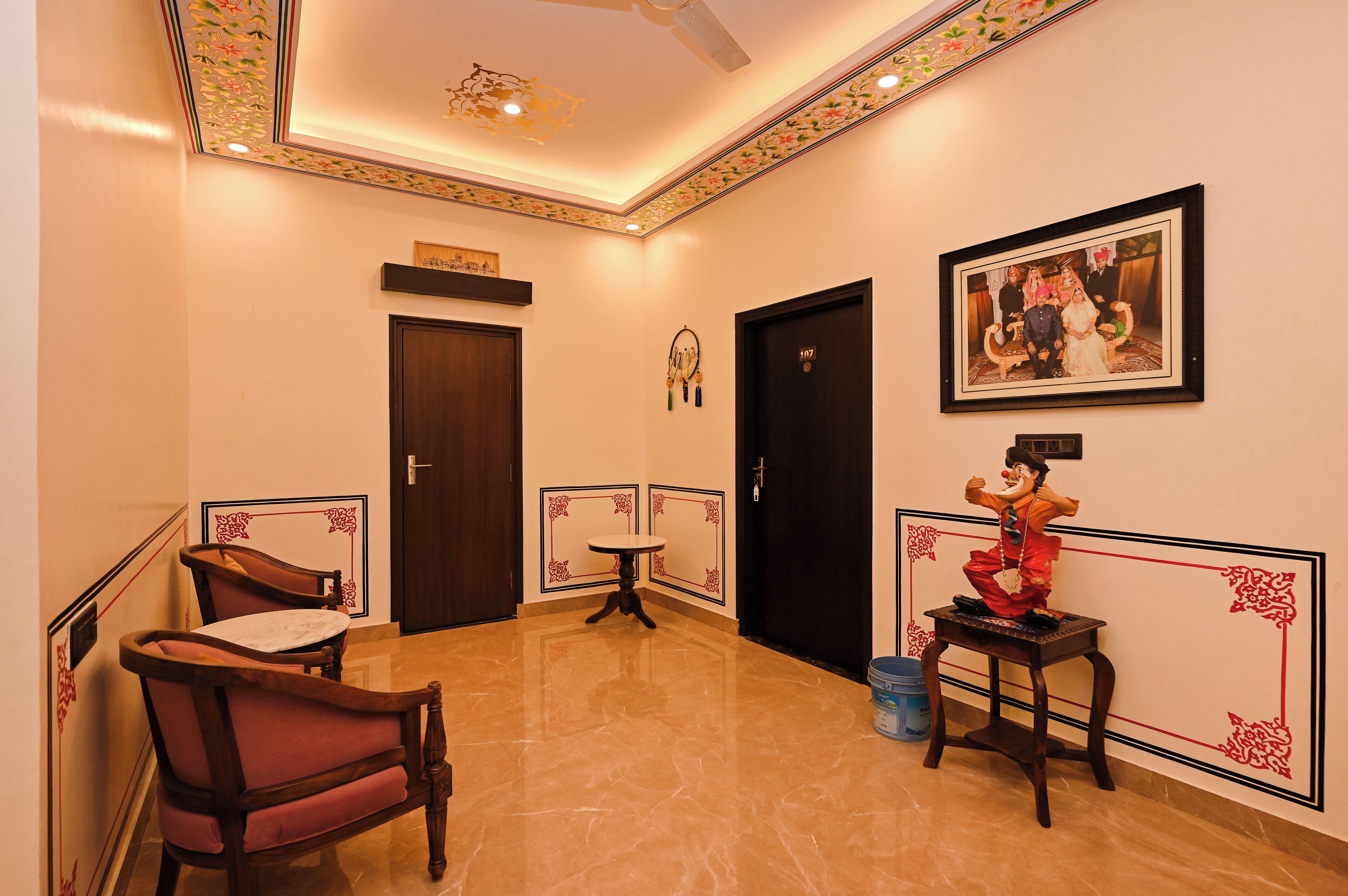 A hotel corridor with a polished floor, a seating area with chairs, a small table, and a framed photo on the wall.