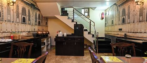 Un interior tradicional con una escalera, una zona de cocina y mesas de comedor.