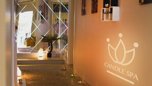 Un pasillo con piso de mármol que conduce a una sala que dice 'CANDLE SPA'.