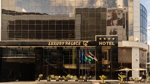 Un edificio moderno con fachada de vidrio, que muestra el rótulo 'Luxury Palace Hotel'.