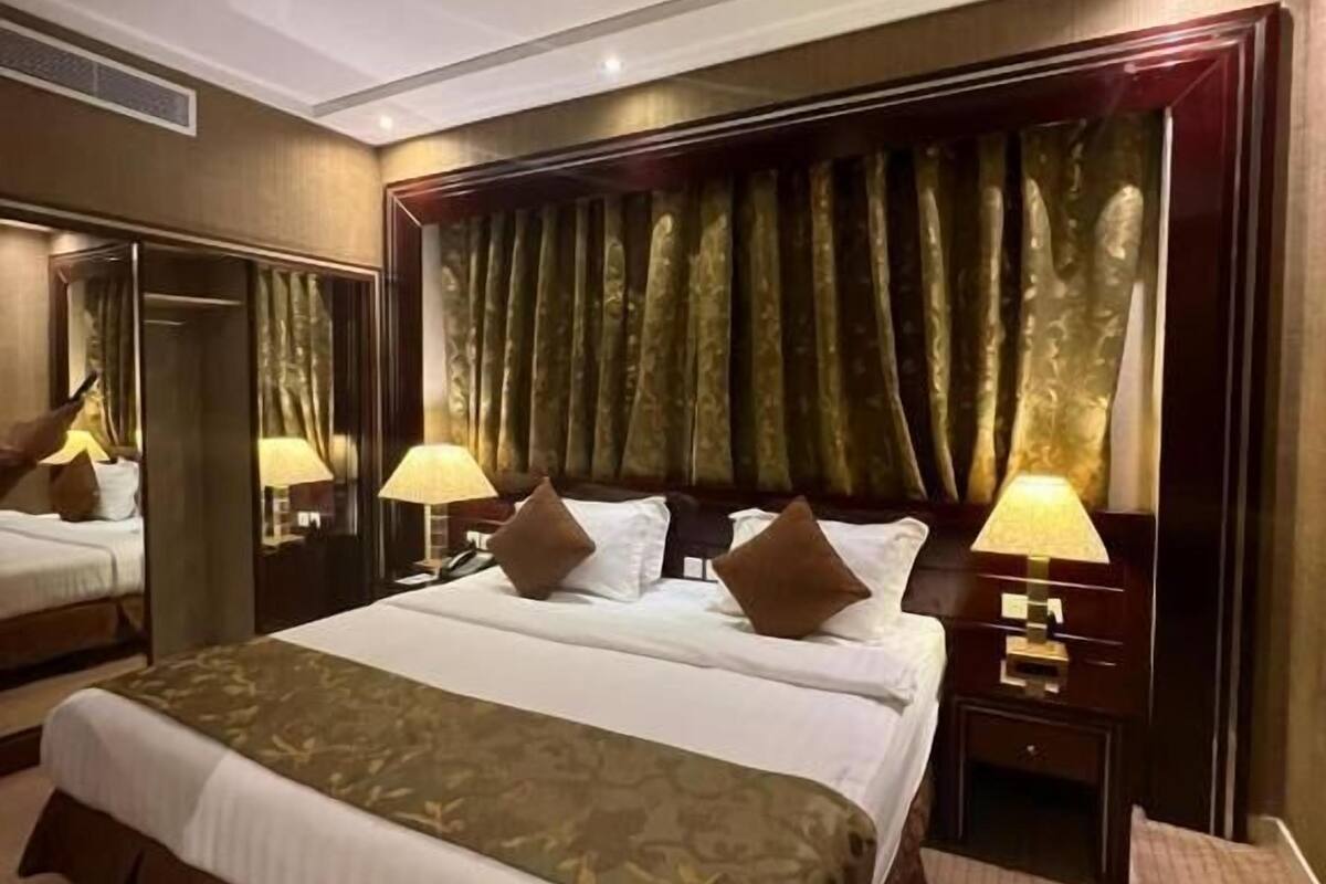A hotel room with a large bed, two bedside tables with lamps, a wardrobe, and a mirror.