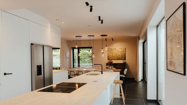 A modern kitchen with a central island, stainless steel appliances, pendant lighting, and a large window providing natural light. - Spacious, sunny luxury vacation home with sauna and garden! (Gistel)