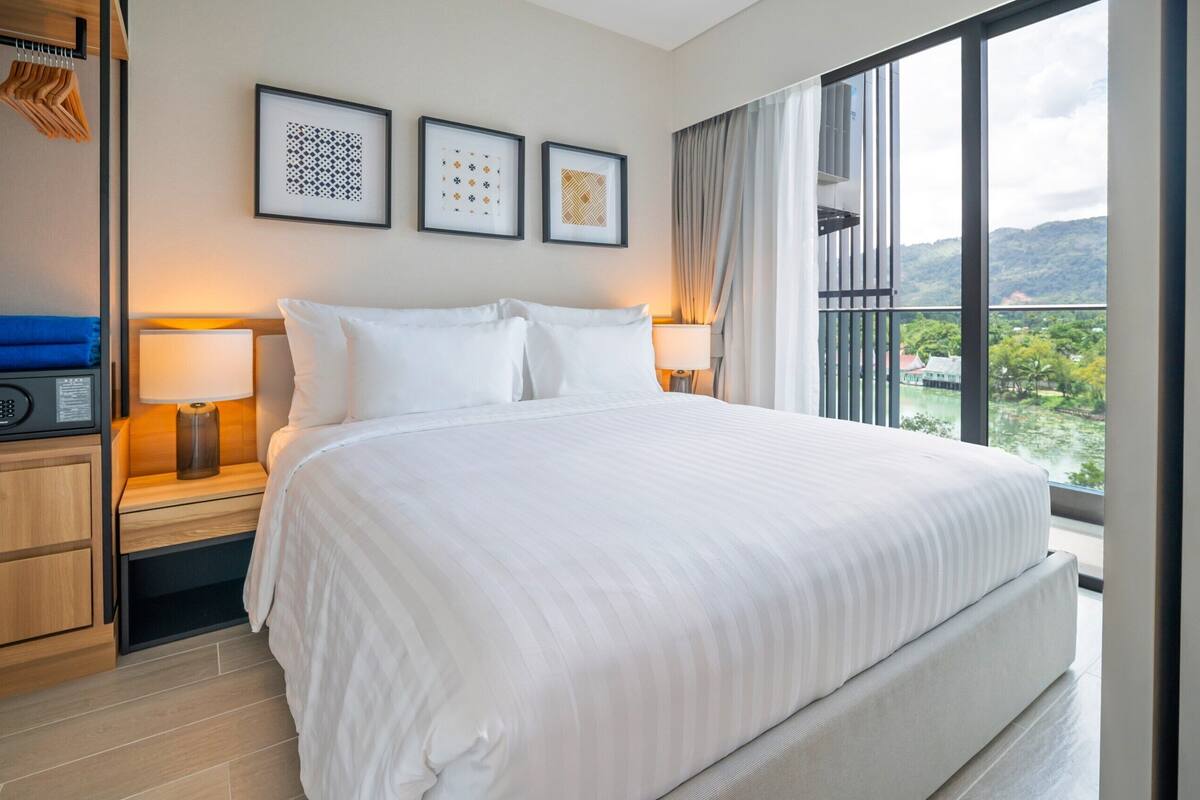 Ein Hotelzimmer mit einem großen Bett, zwei Nachttischen, einem Radio und gerahmten Kunstwerken an der Wand.