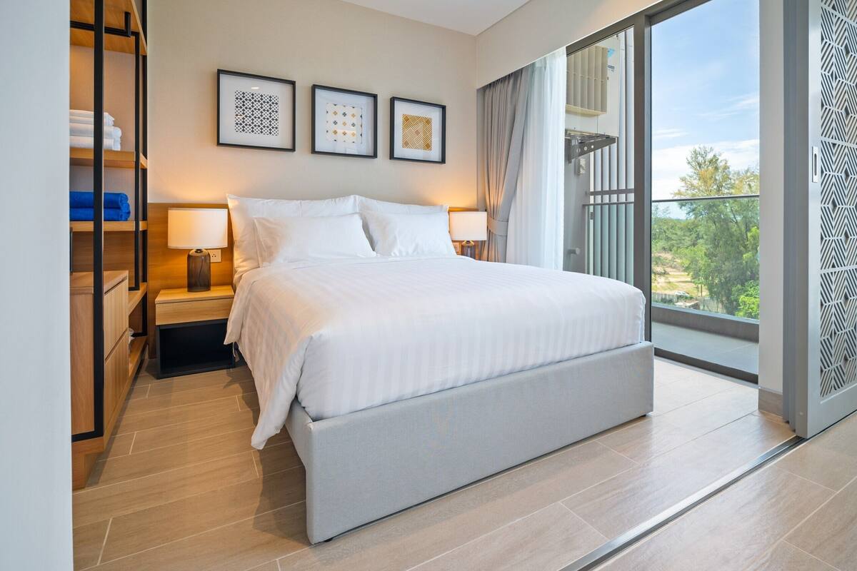 Ein modernes Hotelzimmer mit einem großen Bett, einem Kleiderschrank und einem Balkon mit Aussicht.