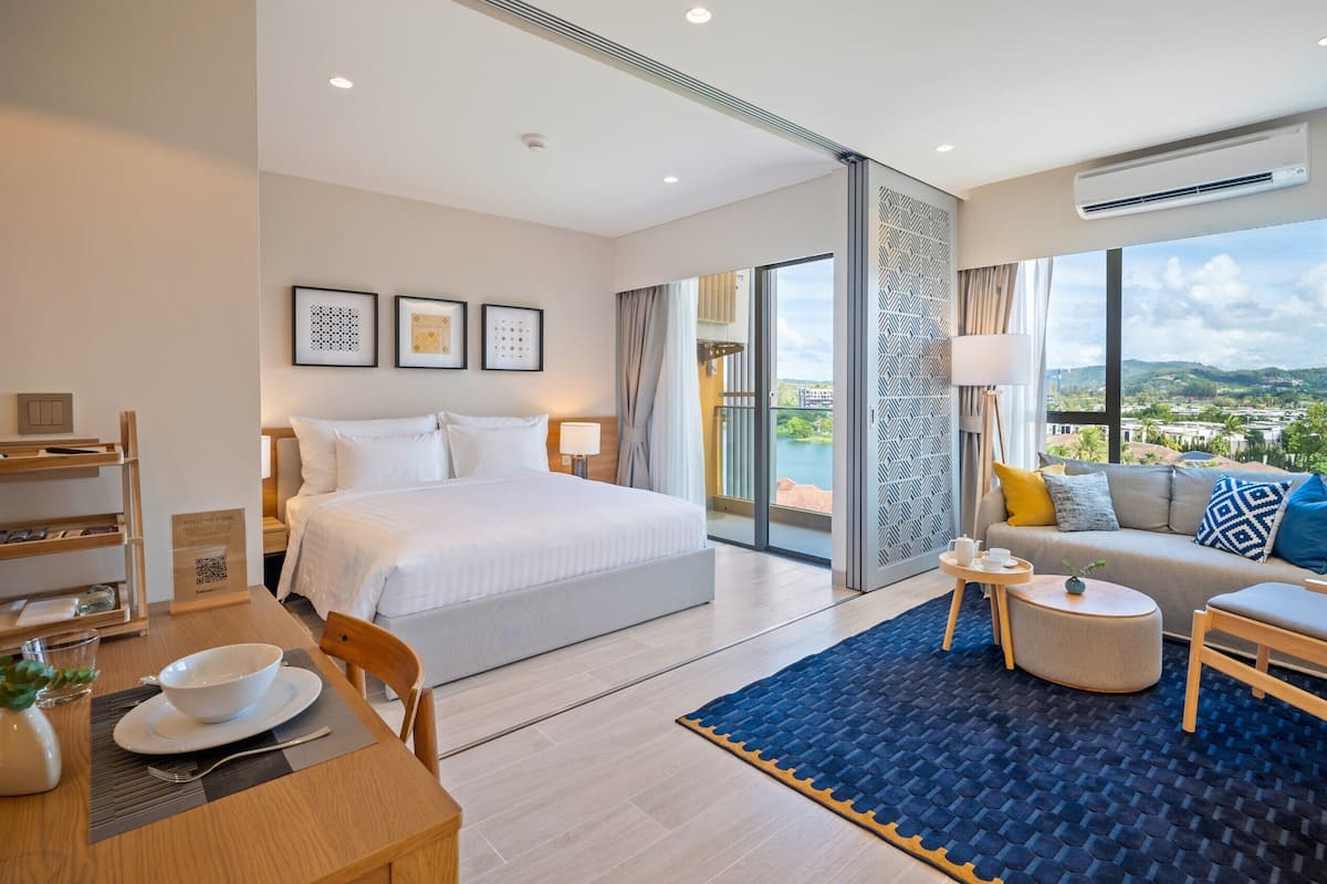 Ein modernes Hotelzimmer mit einem großen Bett, einer Couch, einem Essbereich und Blick auf die Stadt.