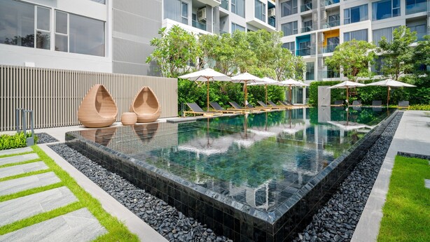 Un espace piscine moderne, avec une piscine rectangulaire, des chaises longues et des parasols.