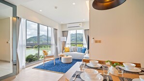 Une chambre d’hôtel moderne dotée d’un coin repas, d’un canapé offrant une belle vue et d’une grande fenêtre donnant sur un paysage pittoresque.