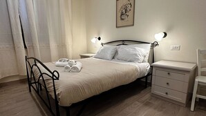 A neatly made bed with a metal frame, two bedside tables with lamps, a small bedside drawer, and a chair. - Double room with private bathroom in Terralba (Oristano) - Mirto (Terralba)