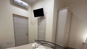 A bedroom with a bed, a wardrobe, a television, and an air conditioning unit. - Double room with private bathroom in Terralba (Oristano) - Mirto (Terralba)